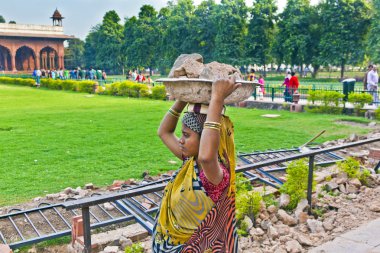 Female worker carries rock waste on her hat clipart