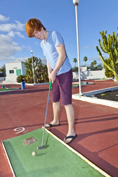 Menino jogando mini-golfe no campo — Fotografia de Stock