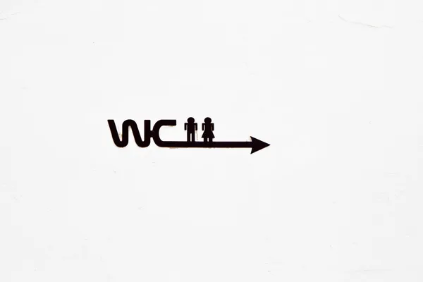 Знак WC с иконой мужчины и женщины на бетонной стене — стоковое фото