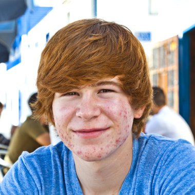 Smart boy in puberty sitting on an outdoor table in the village clipart