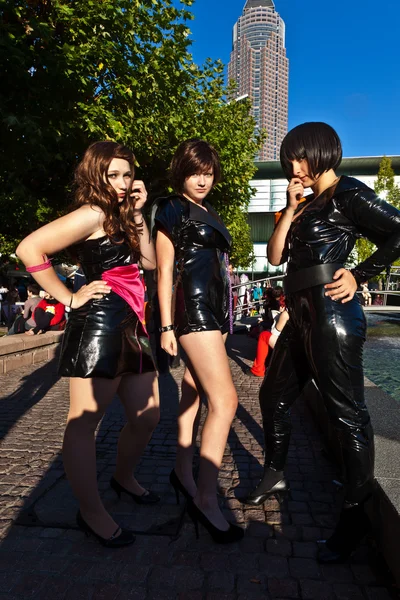 Three girls in black in costumes are posing for photografers — Stock Photo, Image