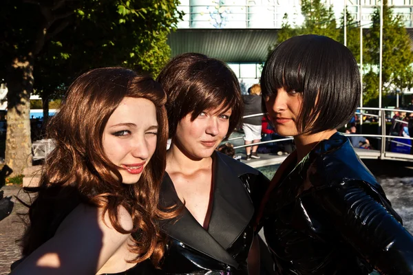 Three girls in black in costumes are posing for photografers — Stock Photo, Image