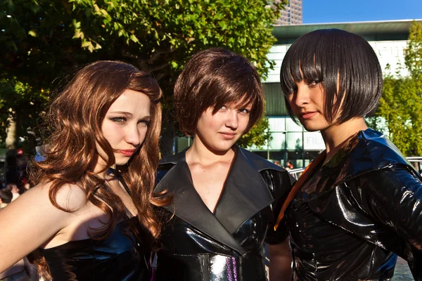 Tre ragazze in nero in costume sono in posa per i fotografi — Foto Stock