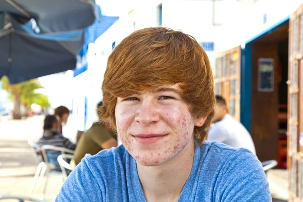 Chico inteligente en la pubertad sentado en una mesa al aire libre en el pueblo —  Fotos de Stock
