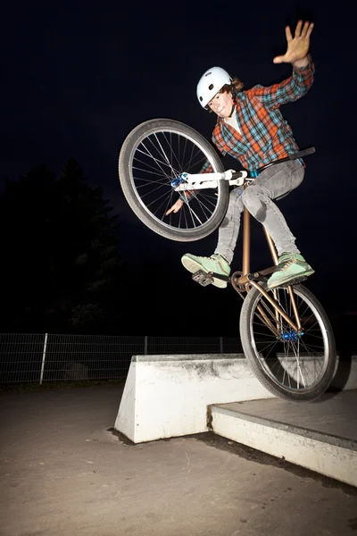 Мальчик прыгает на велосипеде через пандус ночью — стоковое фото
