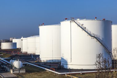 White tank in tank farm with blue sky clipart