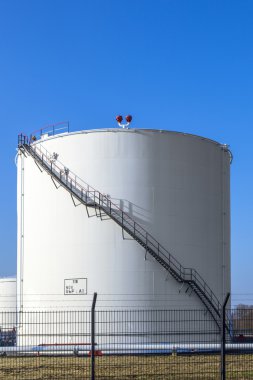 White tank in tank farm with blue sky clipart