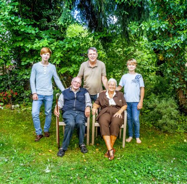 Extended family group posing in the garden with grandparents clipart