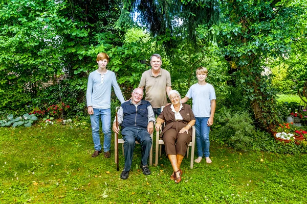 Rozšířená rodina skupina pózuje v zahradě s prarodiči — Stock fotografie