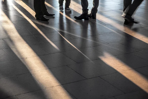 Ноги спешат в аэропорт с посеянными тенями — стоковое фото