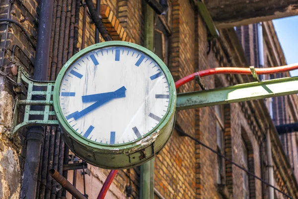 Часы на старой заброшенной фабрике у стены — стоковое фото