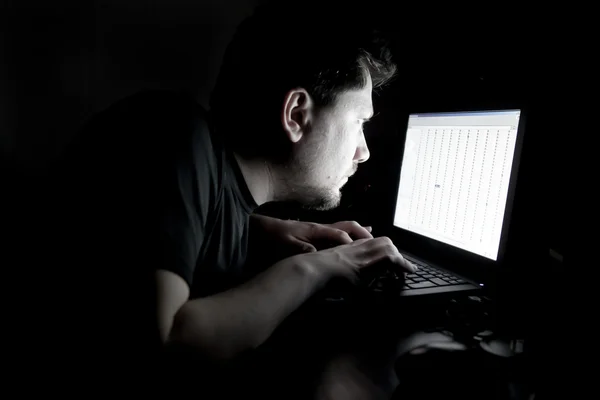 Человек, работающий на ноутбуке в темноте Стоковое Фото