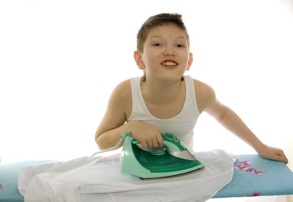 Мальчик гладит рубашку, изолированную на белом — стоковое фото