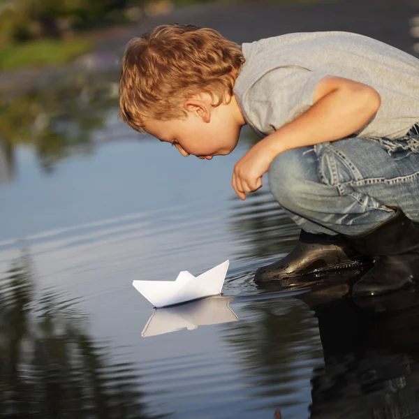 Junge pustet auf Papierschiff — Stockfoto