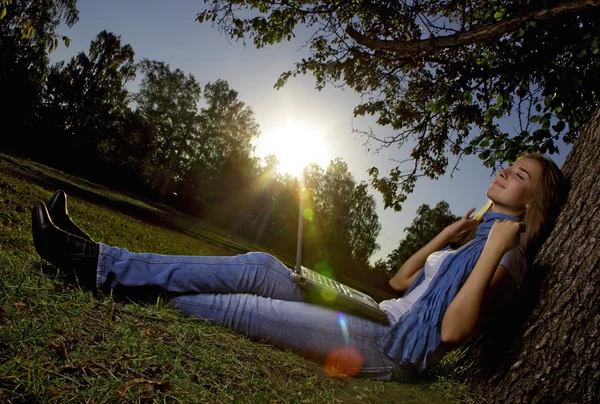 Young beauty girl with laptop in park, photo with artistic lens flare effect — Stock Photo, Image