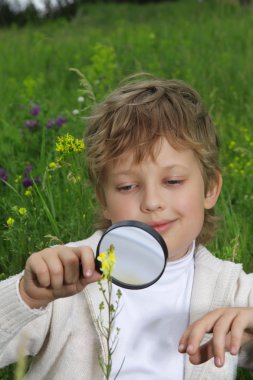 Boy with magnifying glass outdoors clipart