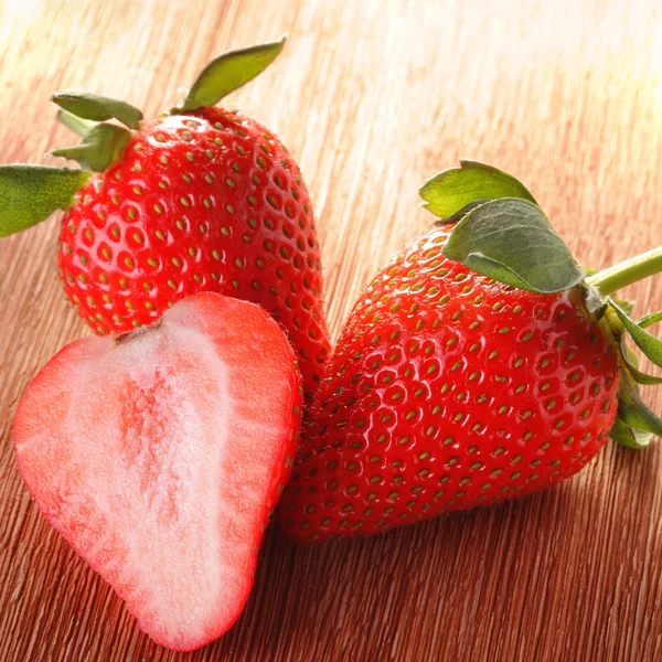 Three strawberries on wood deck — Stock Photo, Image