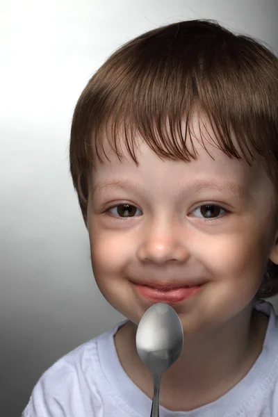 Boy with spoon on grey — Stock Photo, Image