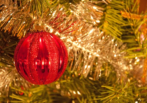 Schöne rote Christbaumkugel, die in einem Baum hängt, der von glänzendem Silber geschmückt ist — Stockfoto