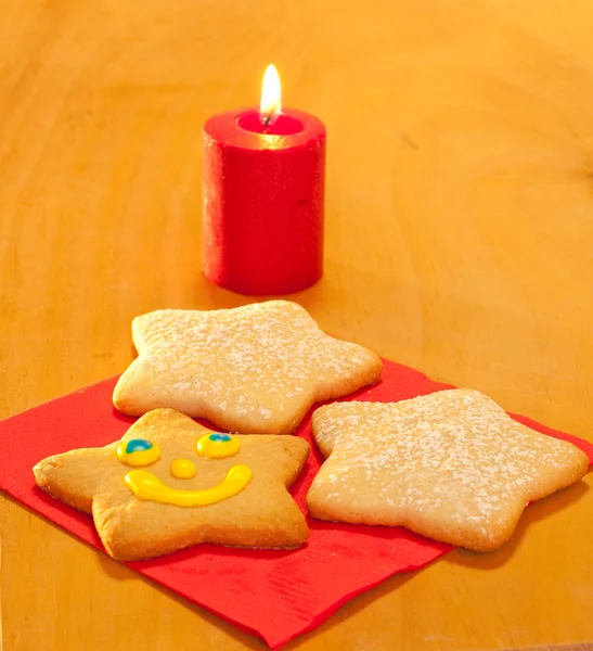 Three star shaped Christmas cookies with a candle — Stock Photo, Image