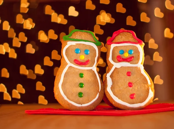 Two snowman shaped Christmas cookies standing on a red napkin — Stock Photo, Image