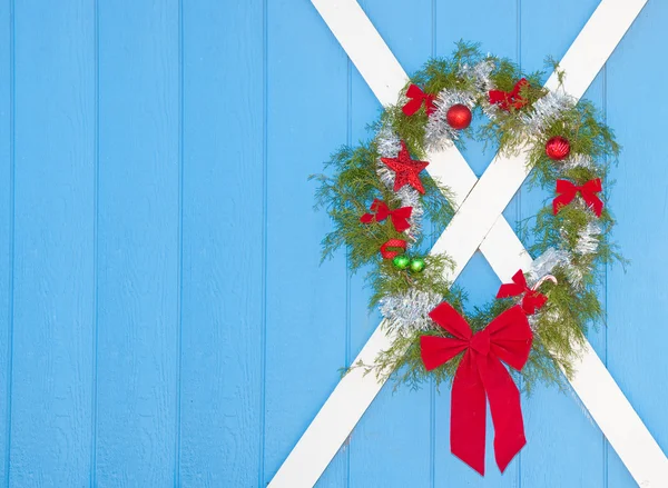Рождественский венок висит на голубой двери сарая — стоковое фото