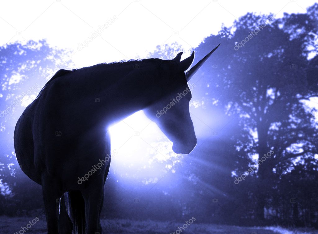Image of a magical unicorn against hazy sunrise with sun rays