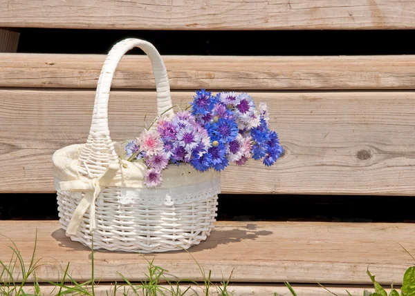 Wicker basket with flowers on rustic steps — Stock Photo, Image