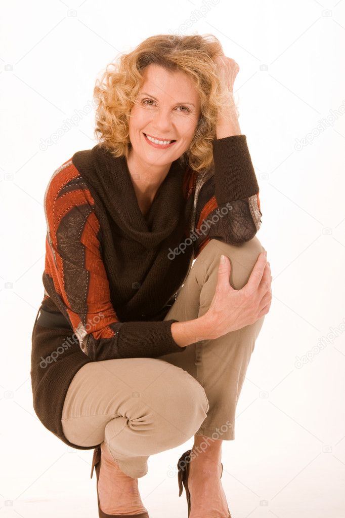 Fashionable elderly woman sitting in a squatting position
