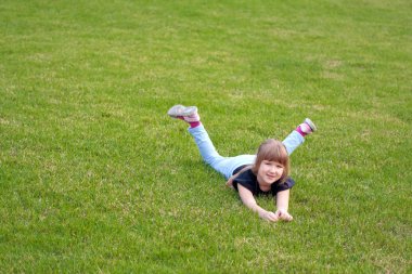 Young smiling girl lying on a lawn clipart