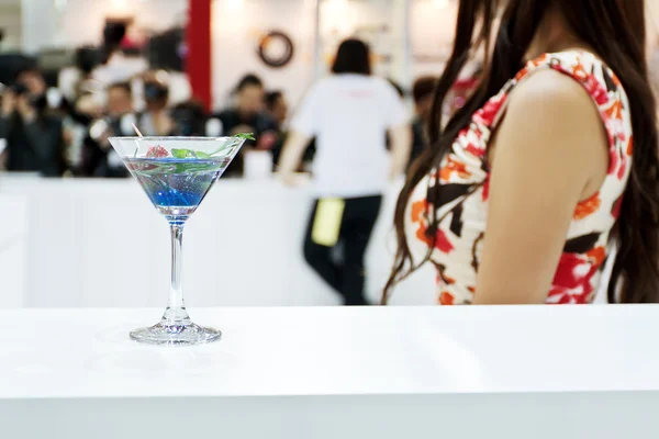 Ett glas blå laguna cocktail med en sexig tjej på bakgrund — Stockfoto