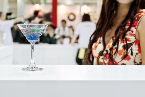 Een glas van blauwe laguna cocktail met een sexy meisje op achtergrond — Stockfoto
