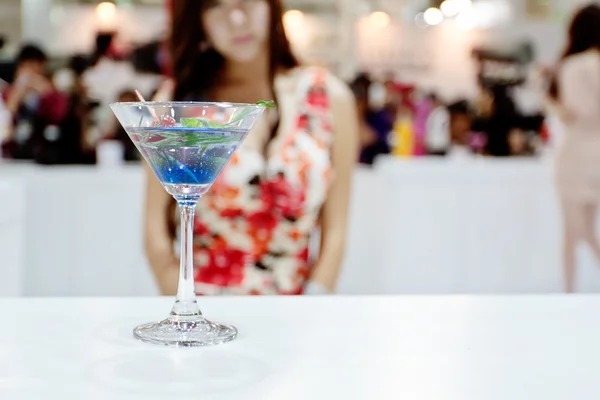 Een glas van blauwe coctail (Ole) met sexy meisje op achtergrond — Stockfoto