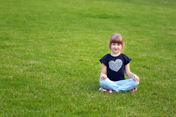 Dziewczynka siedzi na trawnik — Zdjęcie stockowe