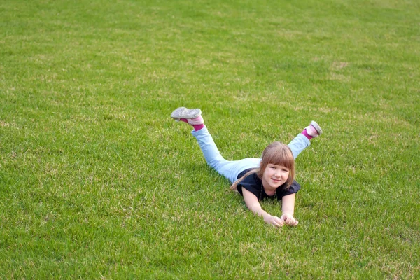 Młoda dziewczyna uśmiechający się leżąc na trawnik — Zdjęcie stockowe