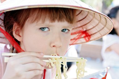 Young girl eating spaghetti in restaurant clipart