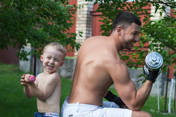 Pai e filho treinam com halteres — Fotografia de Stock