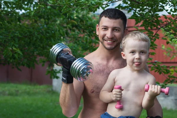 Отец и сын тренируются с гантелями — стоковое фото