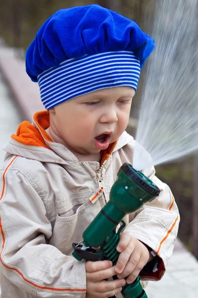 Kleine jongen wateren een moestuin — Stockfoto
