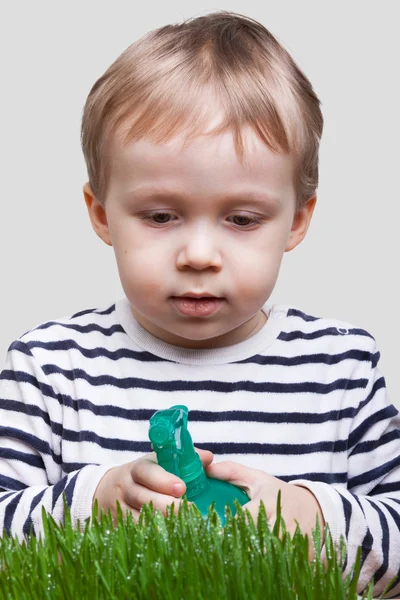 Αγόρι ψεκάζει πράσινο γρασίδι σε στούντιο — Φωτογραφία Αρχείου
