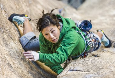 Female climber clinging to a cliff. clipart