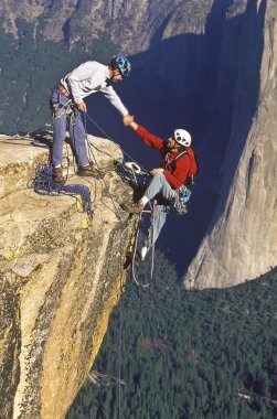 Climbers shaking hands on the summit. clipart