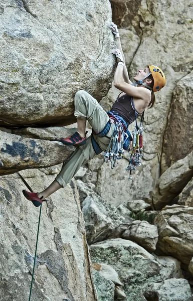 Rock klimmer klampt zich vast aan een steile klif. — Stockfoto