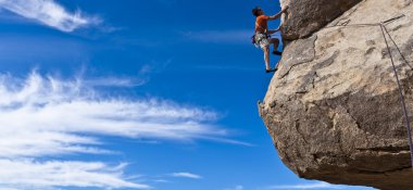 Male rock climber clinging to a steep cliff. clipart