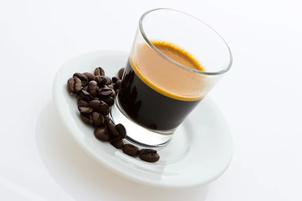 Горячий кофе эспрессо с кофейными зёрнами на маленькой тарелке — стоковое фото