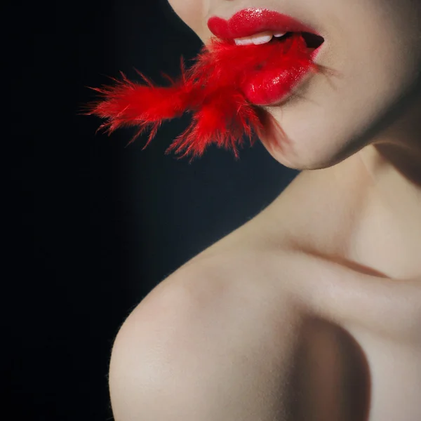 Young woman with feather in her mouth — Stock Photo, Image