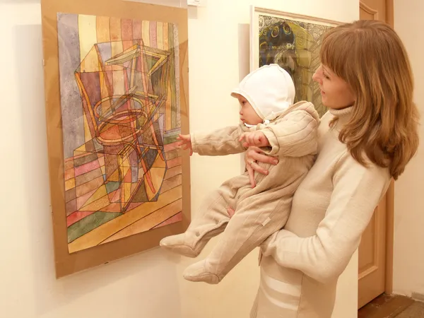 Jeune mère montre au bébé une photo lors d'une exposition — Photo