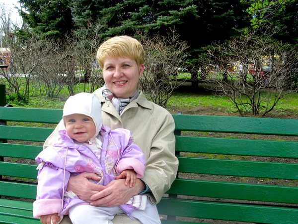 Бабуся з онукою сидить на лавці в парку — стокове фото