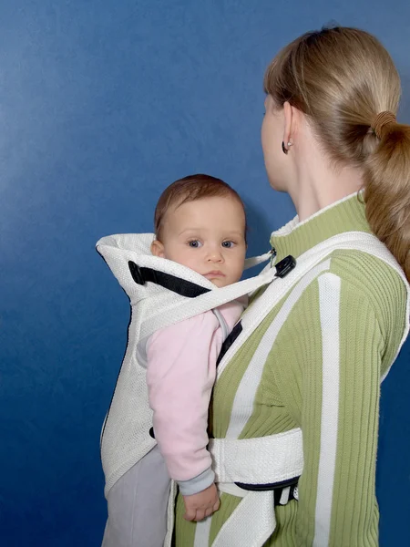 Maman garde le gamin dans une écharpe de bébé — Photo