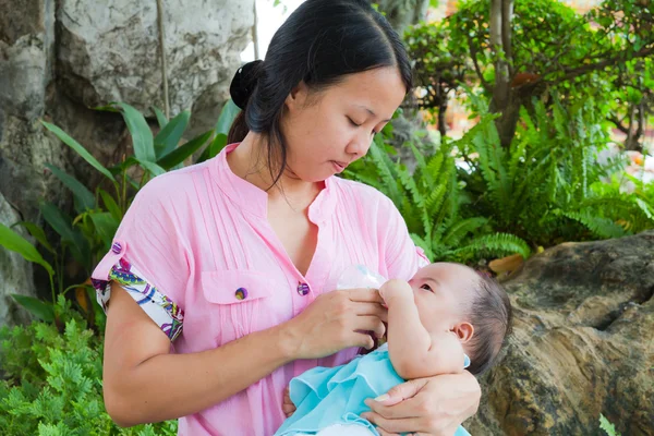 Mulher asiática alimentando seu bebê no parque — Fotografia de Stock